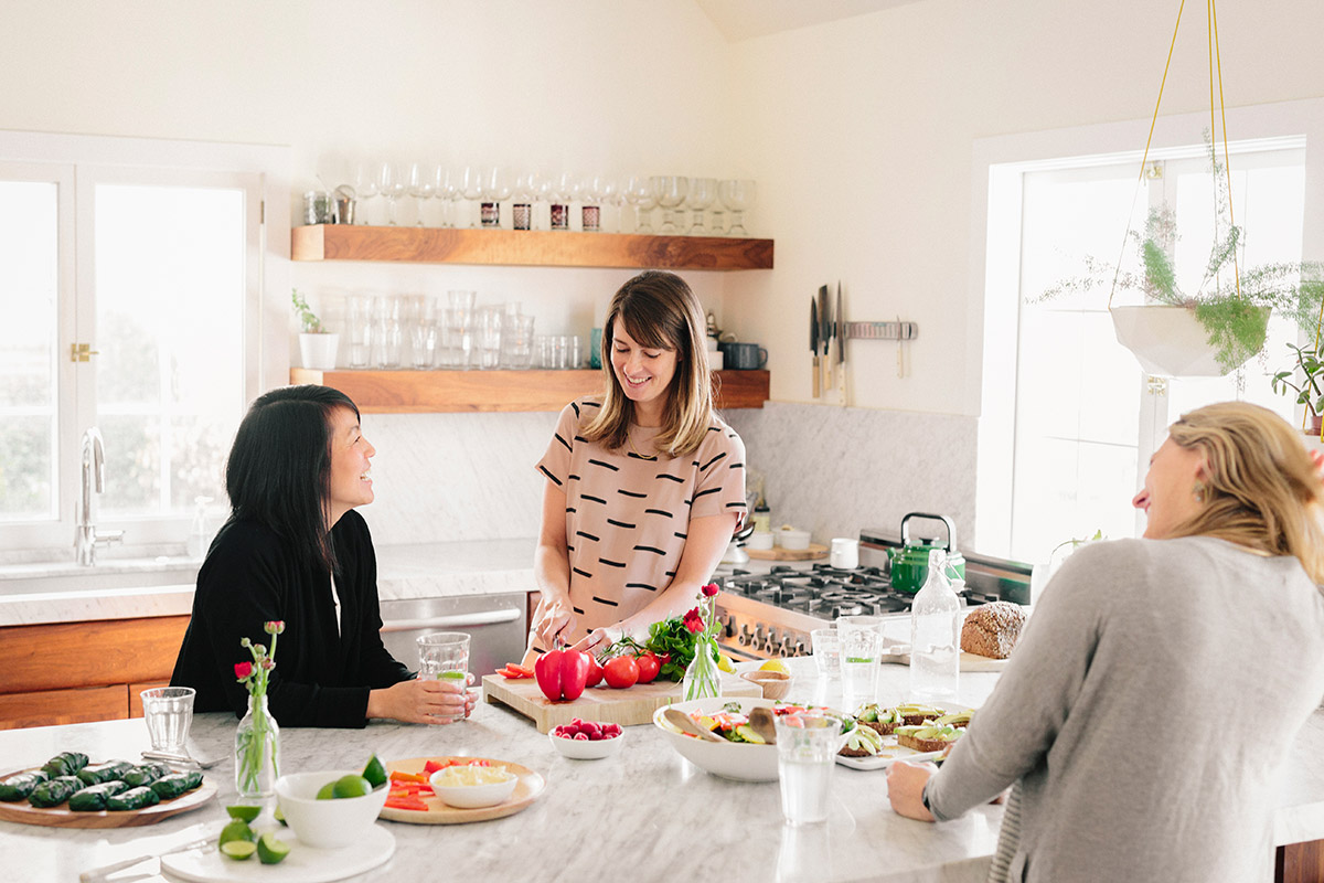 trois femmes préparant un repas dans une cuisine lumineuse